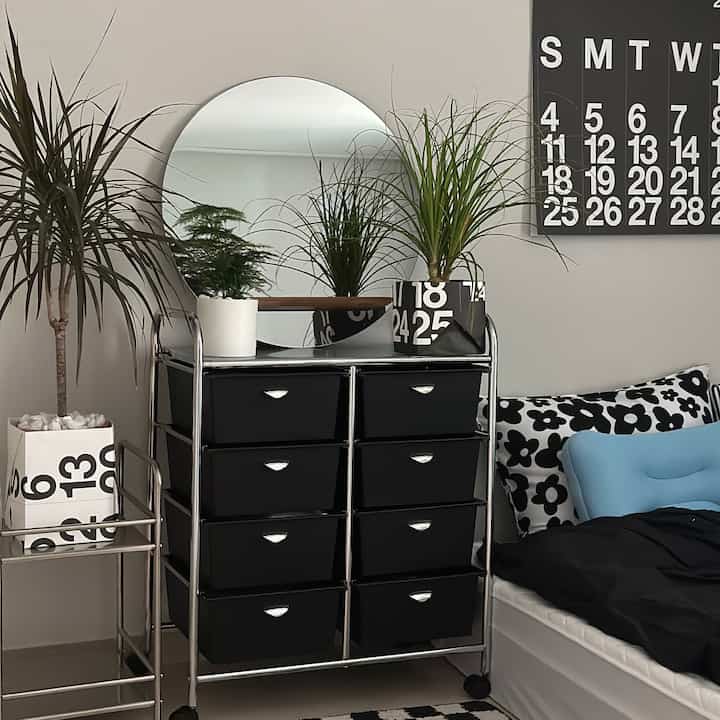 白と黒のトーンの寝室、モダンな4段チェストと植物が配置された北欧風のインテリア