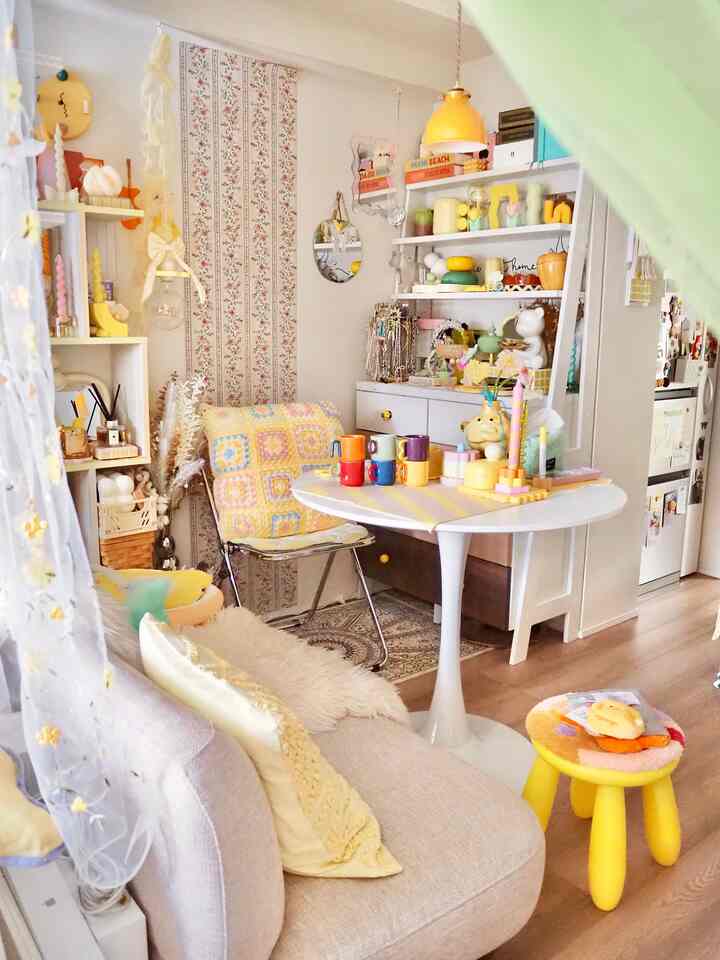 黄色のトーンが印象的なリビング兼ダイニングルーム、ホワイトのダイニングテーブルと多彩な小物が配置された雰囲気のある空間