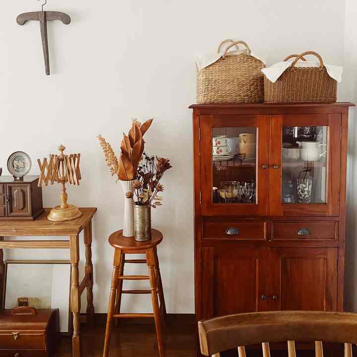 Natural-toned living space featuring a brown cabinet, wooden stool, and rattan baskets creating a cozy vintage atmosphere