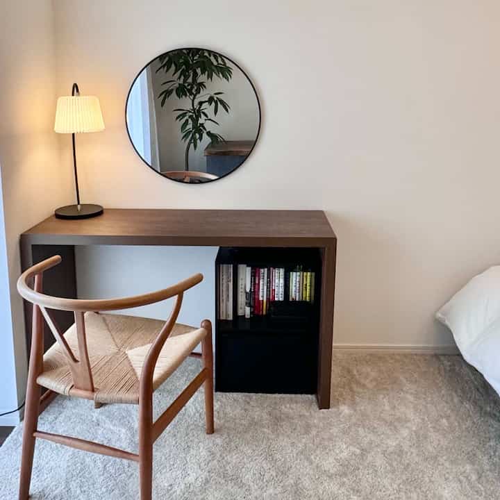 ブラウン調の8畳ワンルームのホームオフィス、シンプルなデスクとYチェア、アイボリーのラグが配置された落ち着いた雰囲気のインテリア