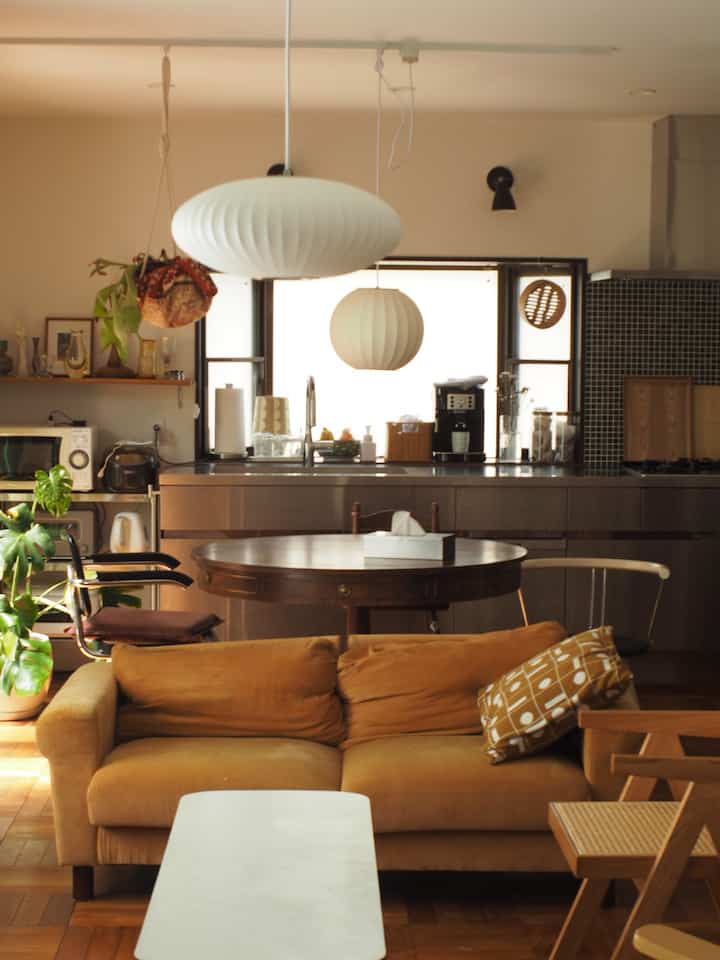Beige and wood-tone Mid-Century Modern living room featuring mustard sofa and round dining table with a warm atmosphere