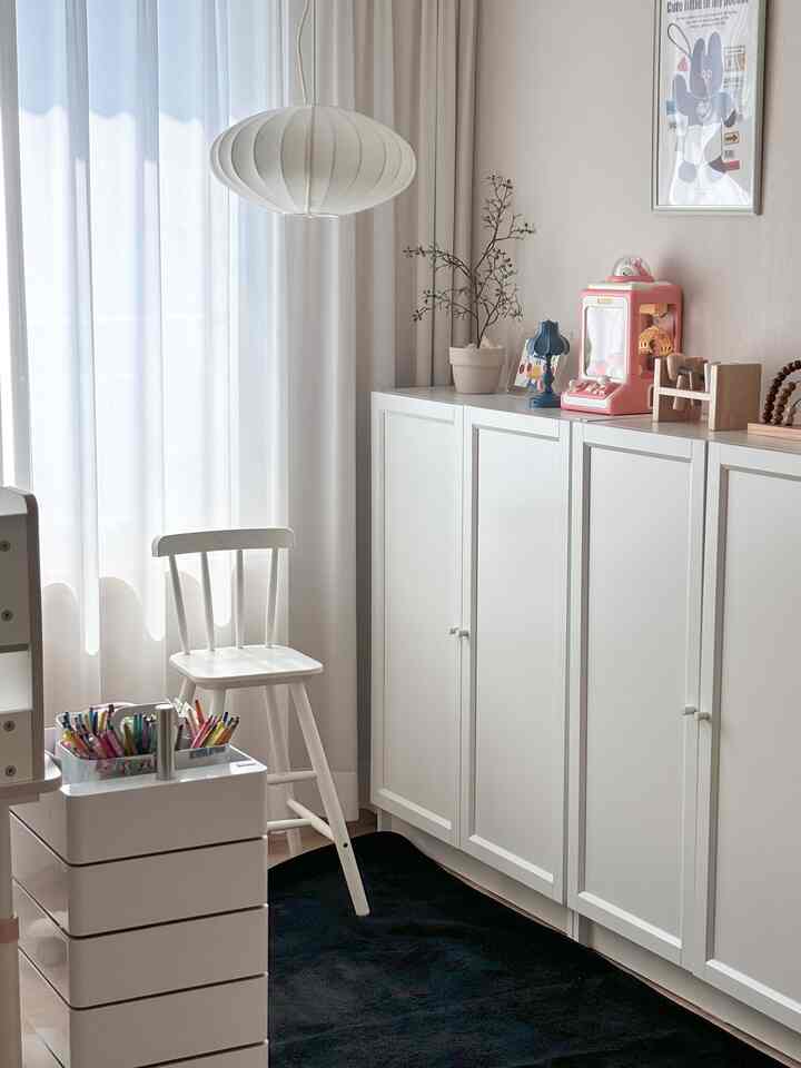 明るいホワイトトーンの子供部屋、子供用チェアと収納棚が配置されたシンプルで清潔感のあるインテリア
