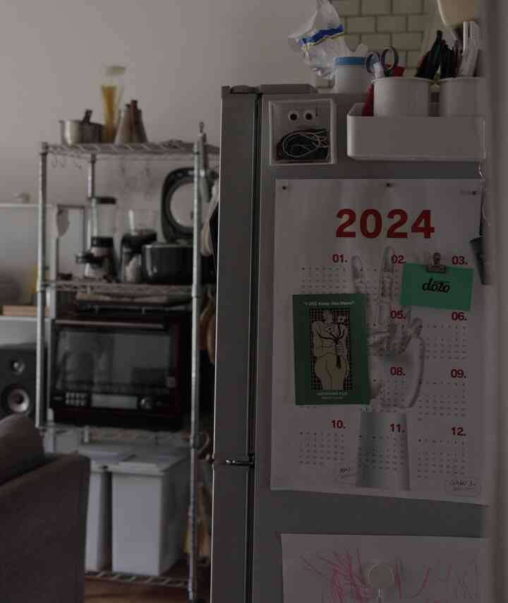 シルバー調のキッチン、シンプルな冷蔵庫正面と右側のごちゃごちゃした収納用品が配置された雰囲気のある空間