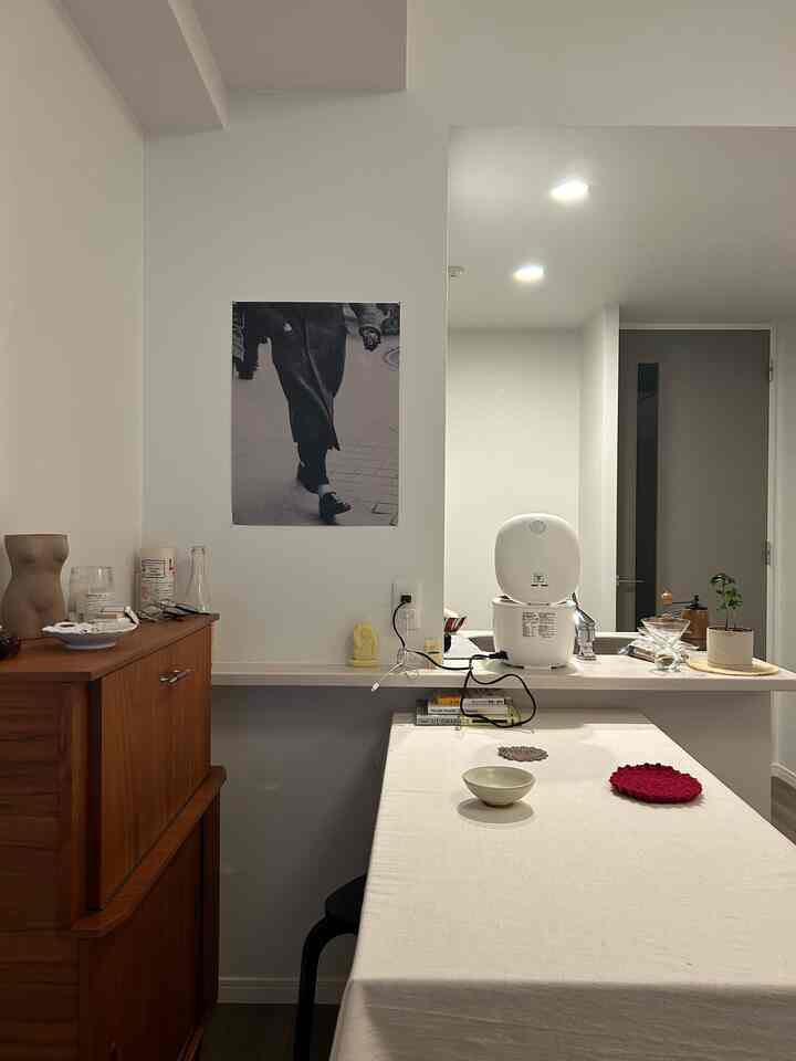 白を基調とした内然な色調のキッチンとダイニングルーム、シンプルで整ったダイニングテーブルと木製収納が配置された空間