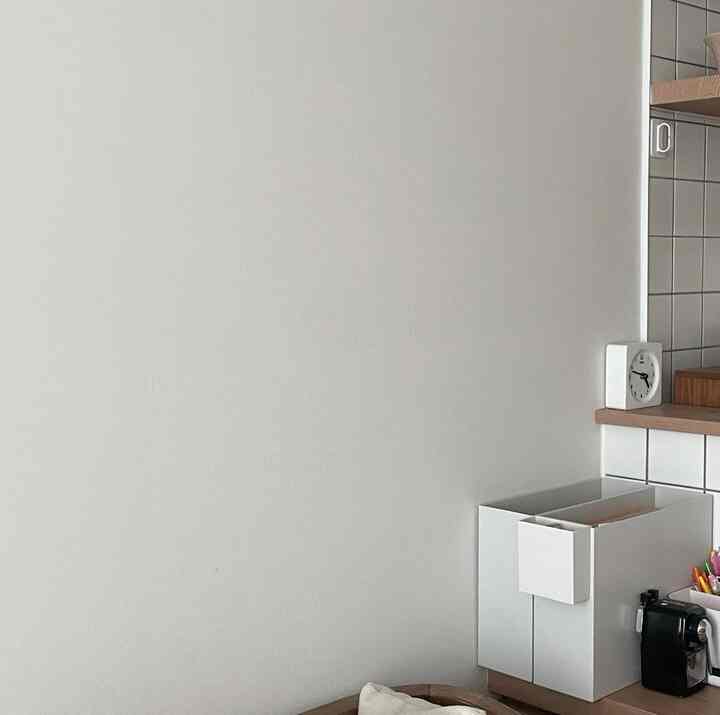 白と木目調が調和した子供部屋、実用的なチェストと静かな時計があるシンプルな空間