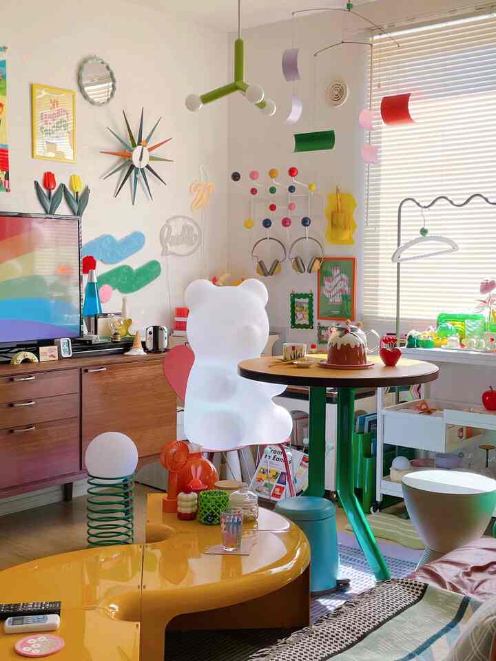 Pastel and vivid colorful living room styled as kids' room featuring a large jelly bear lamp and round dining table