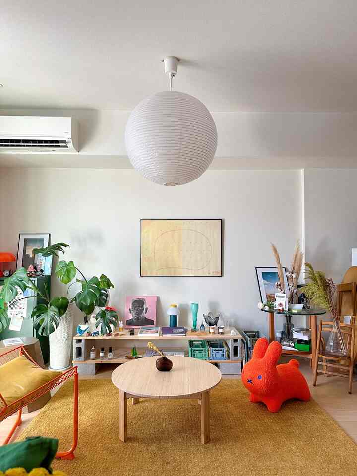 黄色調のリビング、丸いコーヒーテーブルとオレンジの動物型ペットベッドが配置された居心地の良い空間