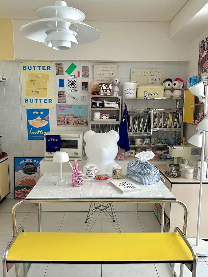 白と黄色のトーンでまとめられたダイニング、中央にかわいいクマ形の椅子とペンダントライトが配置された雰囲気のある空間