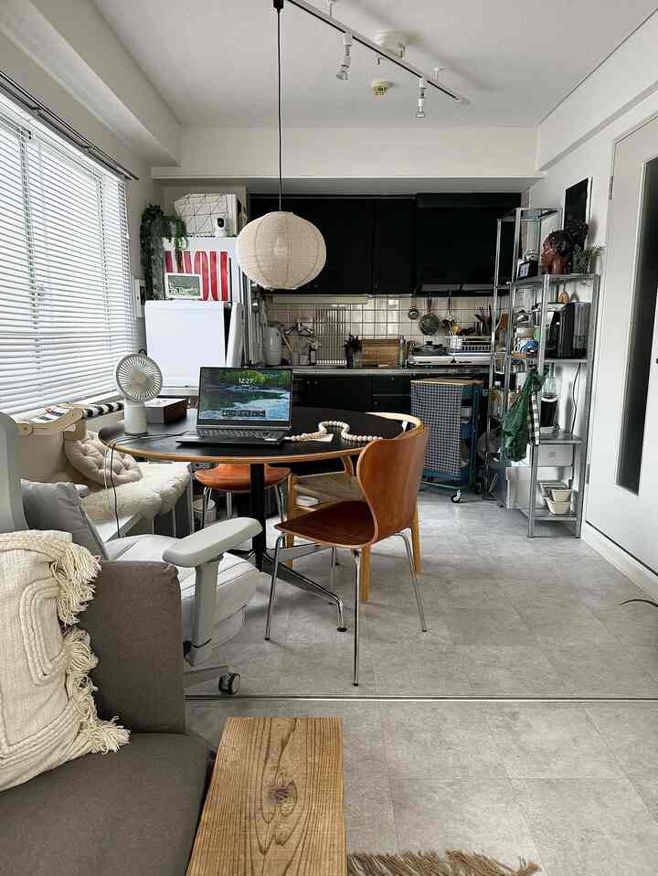 明るいグレーの床とナチュラルカラーの家具が配された一人暮らしのダイニング、シンプルなインテリアとペンダントライトが印象的な空間