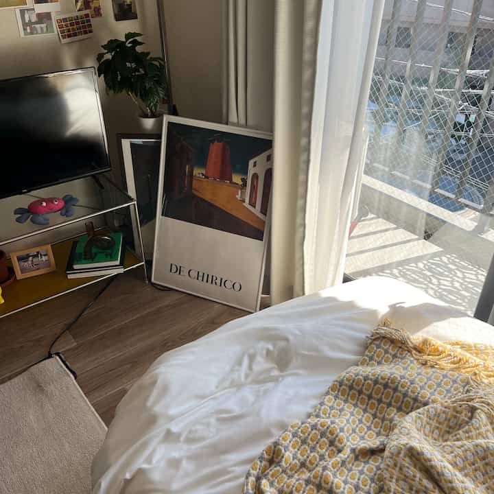 Soft white tone and natural wood 8-tatami studio bedroom featuring artwork, plants, and cozy ambiance