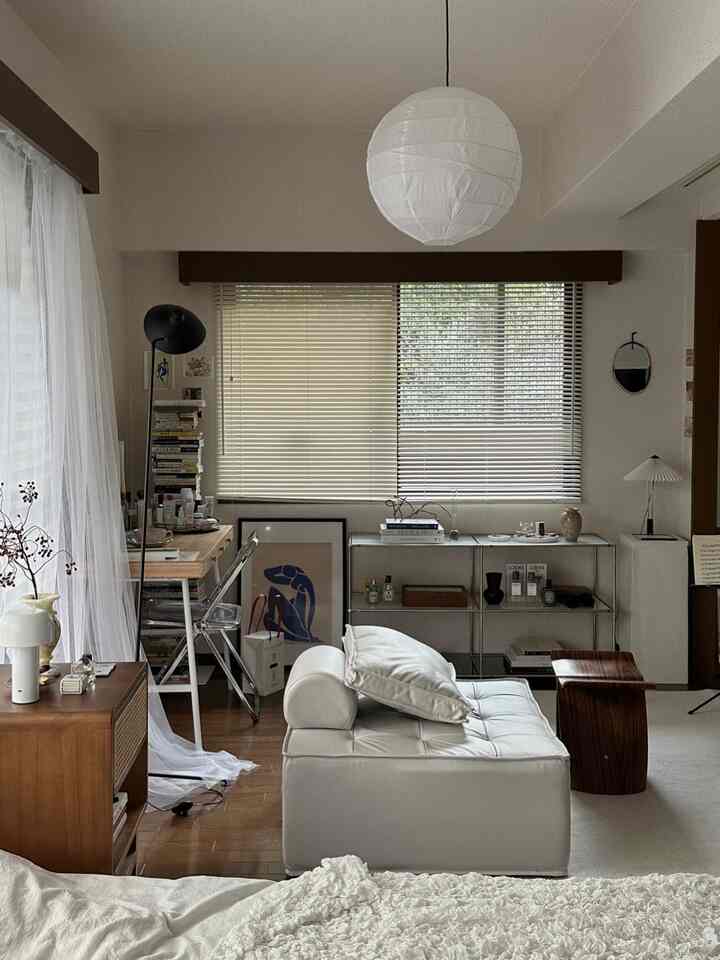 White and wood tone studio apartment living room featuring a modular sofa and small workspace with a natural modern vibe