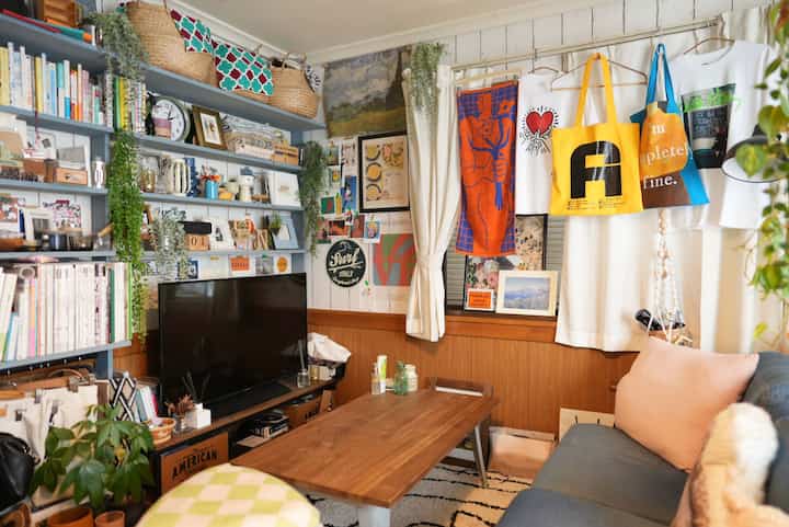 Natural wood tones and white curtains in a living room, decorated with colorful posters and plants creating a cozy atmosphere