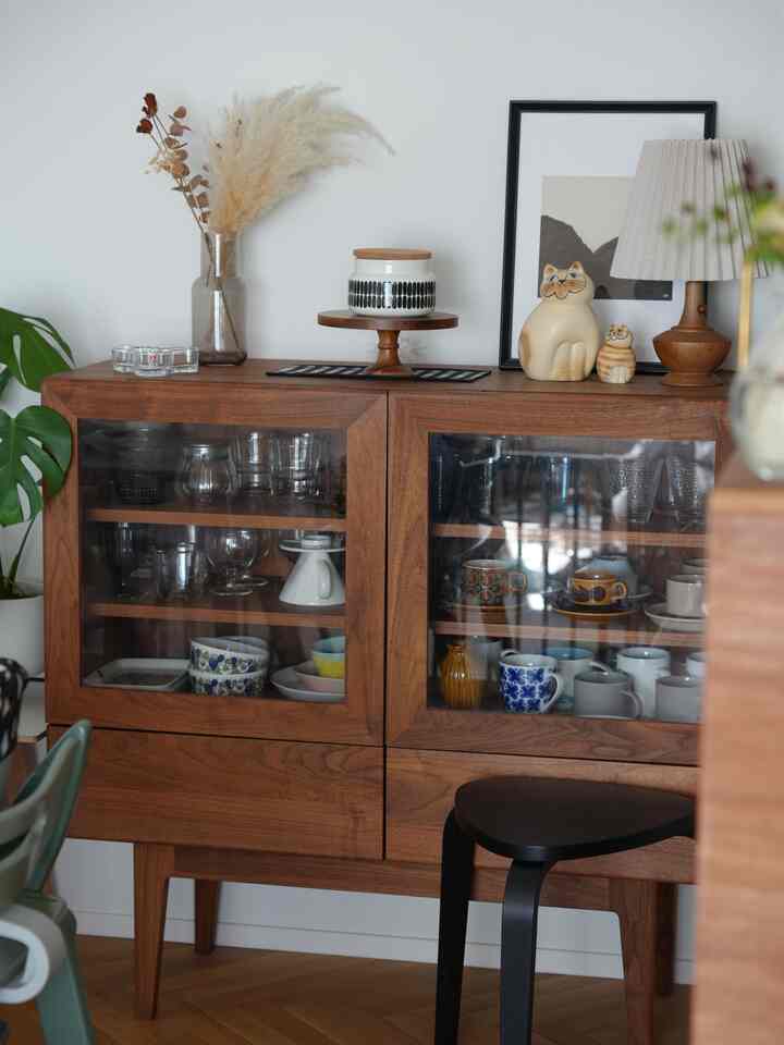 木目調のキャビネットと白い背景の印象的な空間、ドライフラワーとオブジェが配置されている。