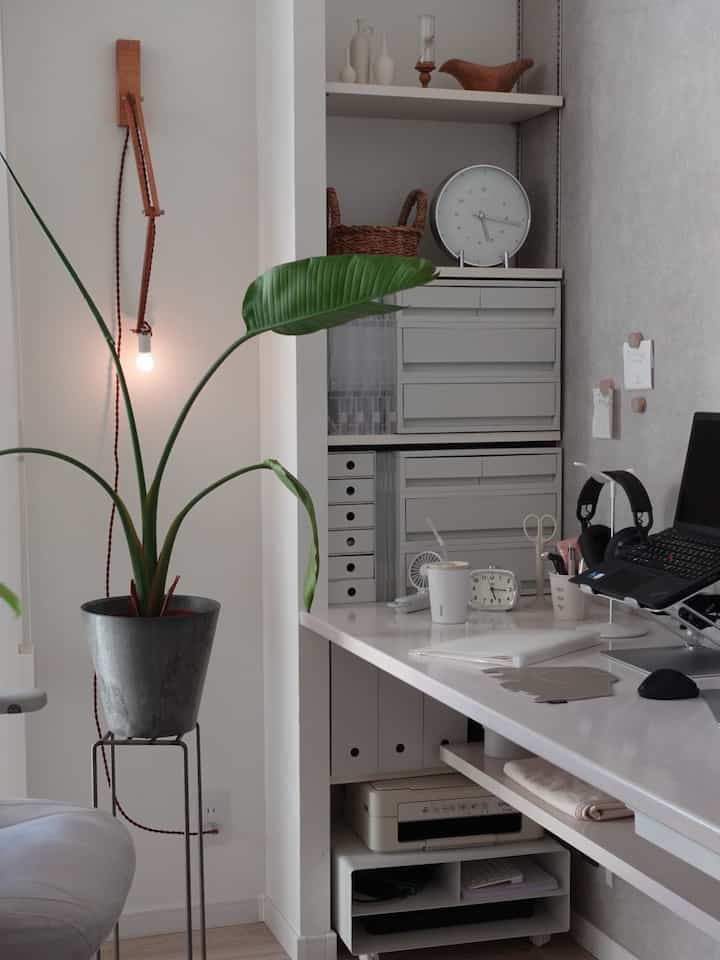 White-toned home office workspace featuring modern desk, storage units, and silver metallic accessories creating a clean atmosphere