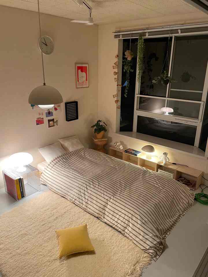 ベージュ色調の寝室、ストライプの掛け布団とテーブルランプが配置された雰囲気のある空間