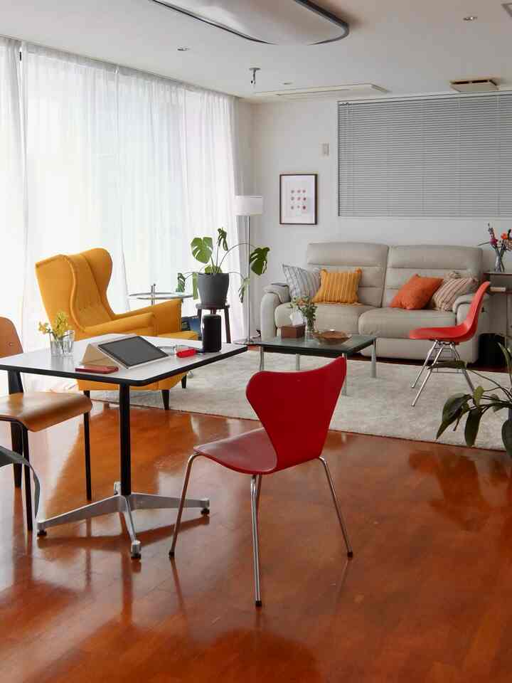 明るい色調のリビングとダイニングルーム、黄色いアームチェアと赤い椅子が調和したモダンな空間