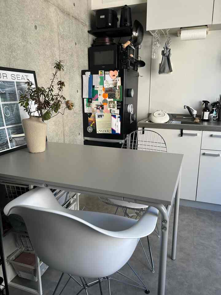 グレーとホワイトの色調のキッチン空間、イームズの成形プラスチックアームチェアとワイヤーチェアが配置されたシンプルでミニマルな雰囲気のインテリア