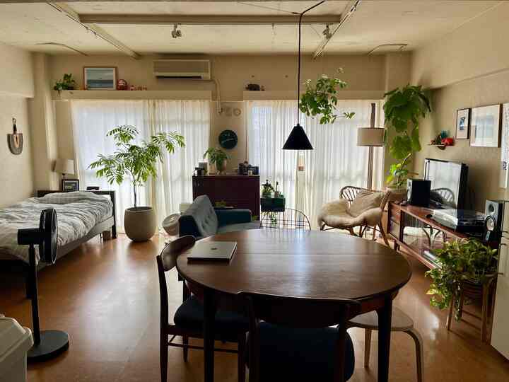 Natural wood tones and green plants compose a single-person studio living and dining space