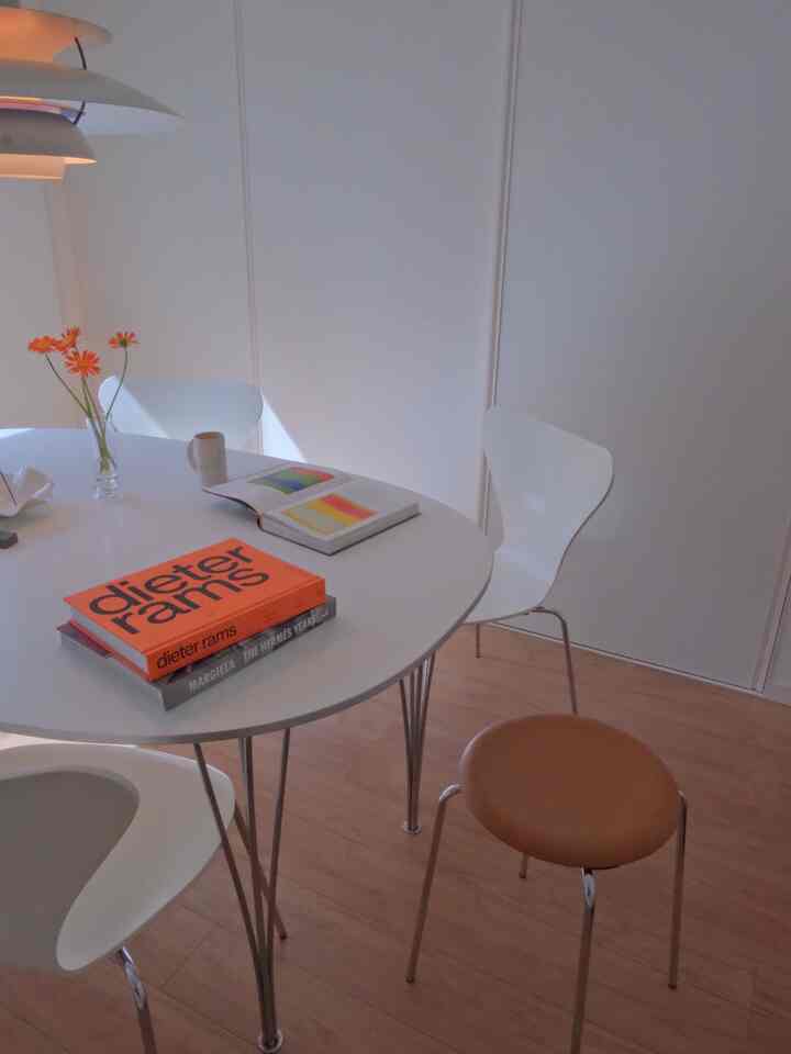 White and brown toned dining room featuring a round dining table, stools, and chairs arranged in a minimal style
