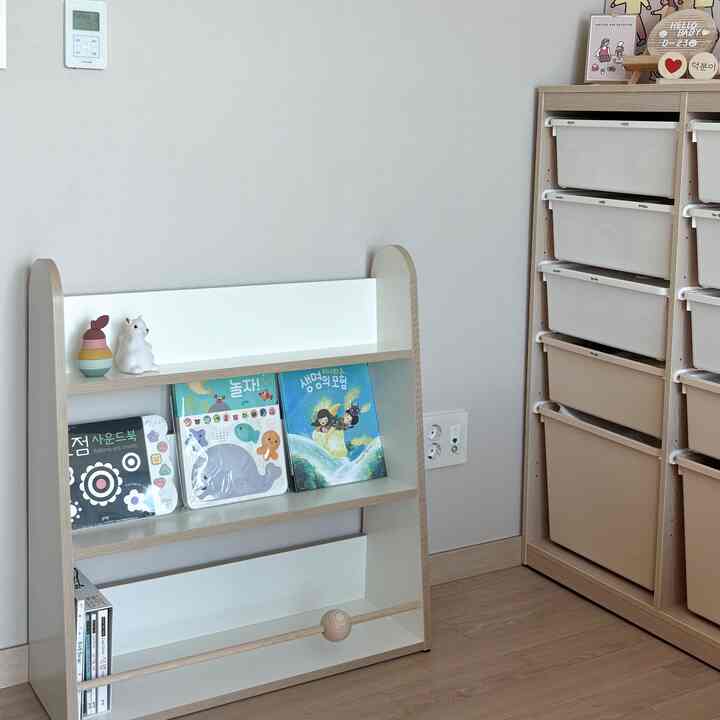 ベージュとナチュラルカラーの子供部屋、本棚と収納キャビネットが配置された落ち着いた雰囲気のインテリア