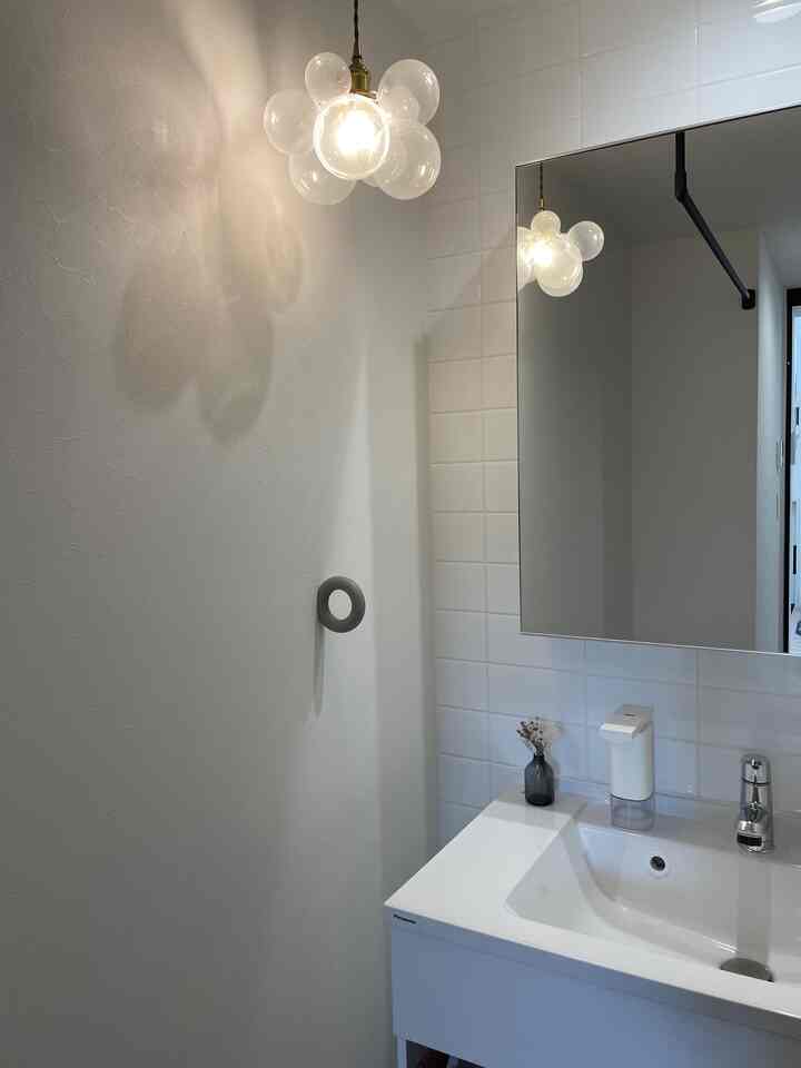 White-toned bathroom featuring a sink, large mirror, and cluster pendant light with a clean atmosphere
