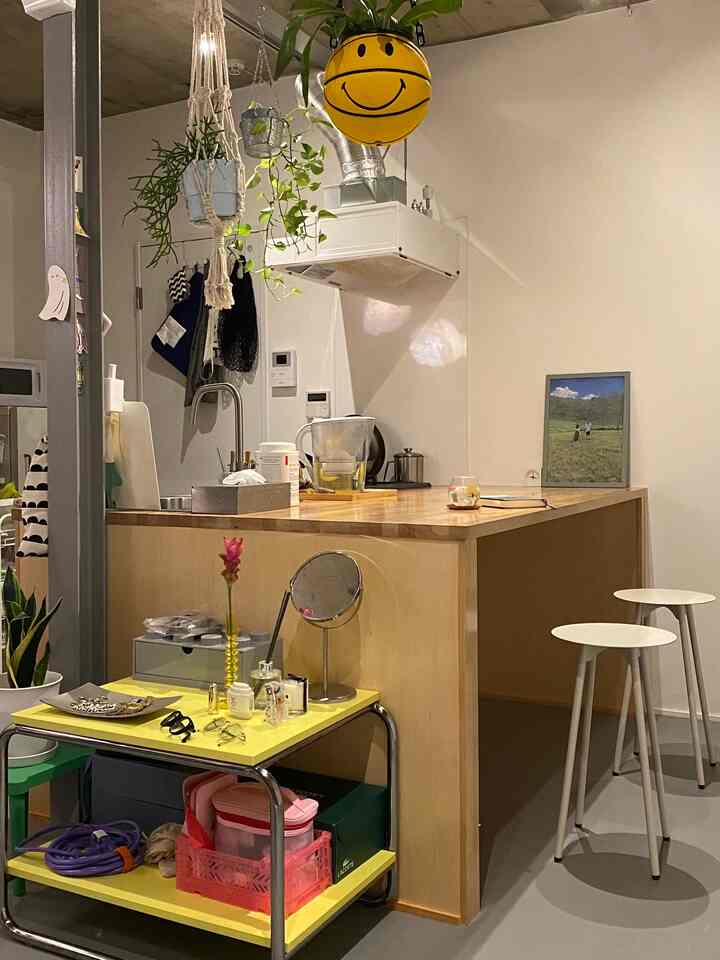 Beige and yellow toned kitchen space featuring wooden counter, hanging plants, and side table with cozy atmosphere