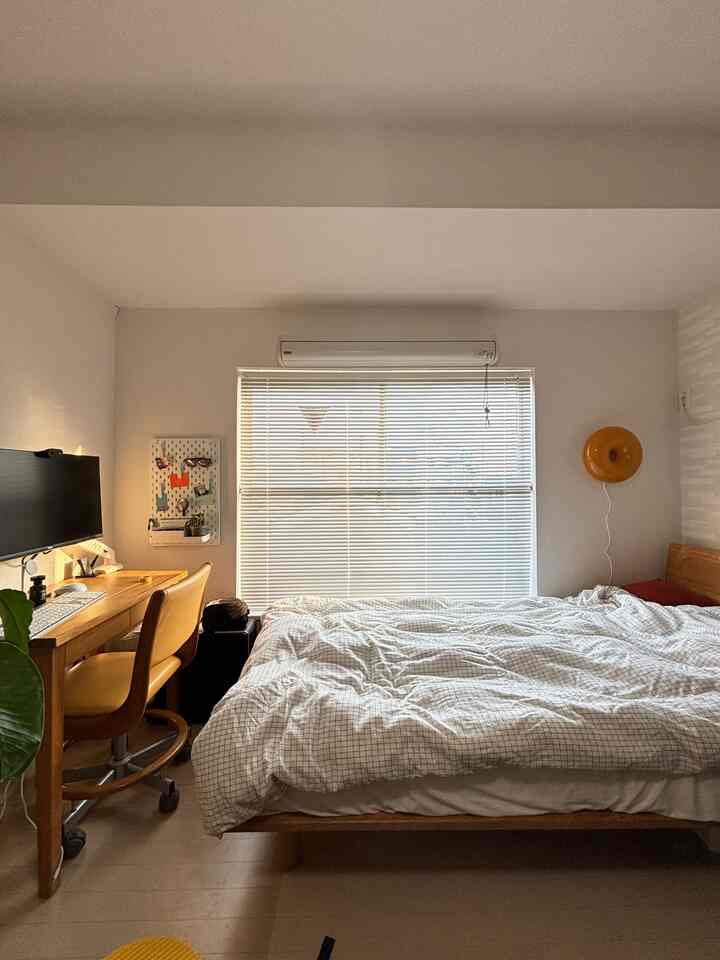 Natural wood tone and white 1K studio bedroom featuring a workspace by the window with desk and office chair, cozy atmosphere