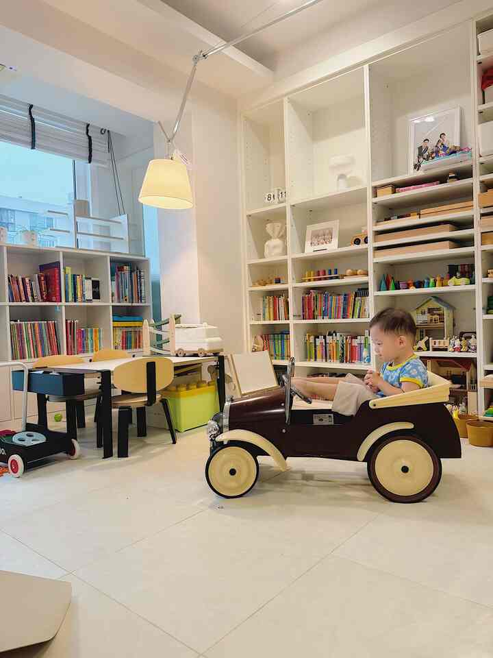 白を基調とした子供部屋、絵本棚とおもちゃの車が配置された明るく落ち着いた空間