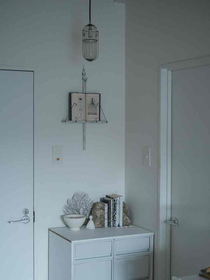 Simple interior corner with white toned storage cabinet, decorated wall art book and accessories