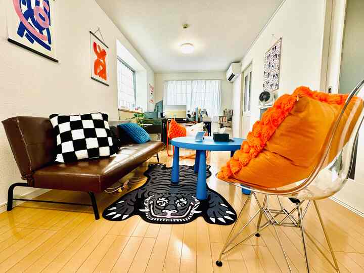 Bright wood tone living room featuring a black tiger rug and blue round table centrally placed with modern furniture accents