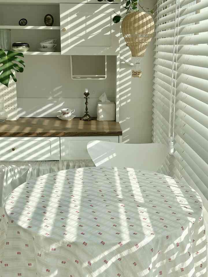 明るいホワイトとブラウンのナチュラルなダイニング、丸テーブルとすっきりした収納が配置された温かみのある空間