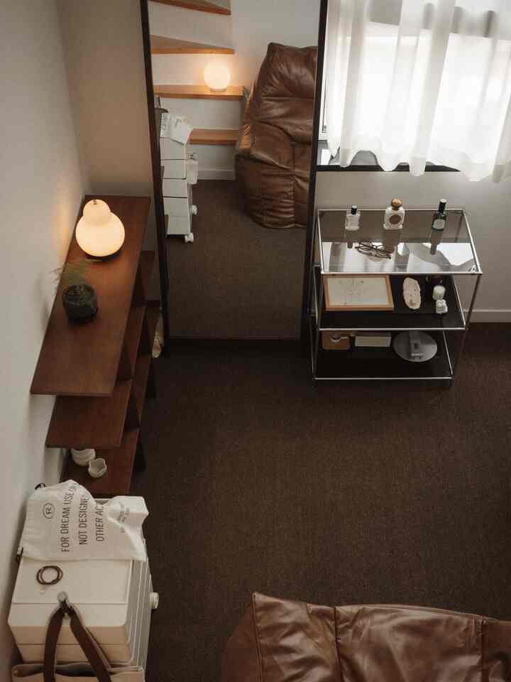 ブラウンのカーペットとビーズクッション、全身鏡と木製の棚が配置された温かみのあるリビングルーム