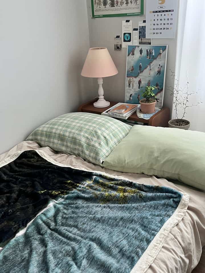 Natural-colored cozy bedroom featuring a bed, nightstand with table lamp, and decorative plants