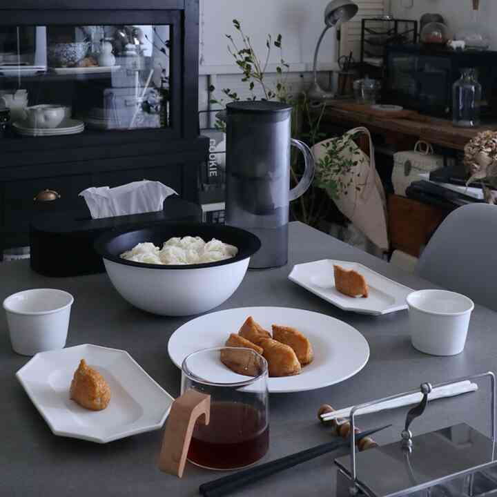 グレーのテーブルの上に白い皿とボウルが置かれたナチュラルモダンなキッチンの空間