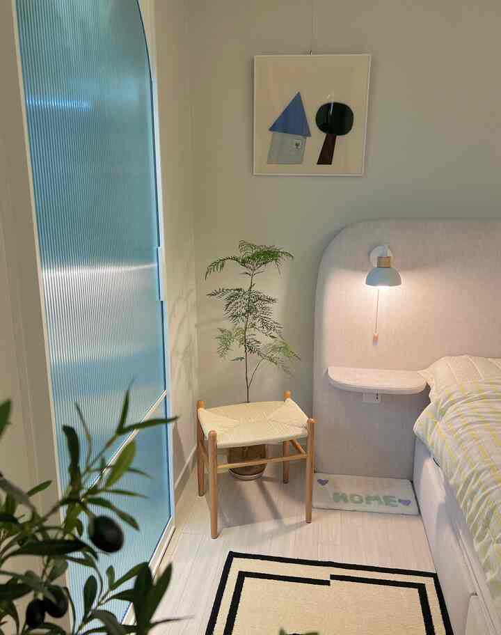 Natural-colored bedroom featuring wooden stool, green plant, and a warm cozy atmosphere