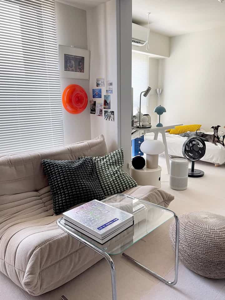 Beige sofa and white walls with a bed in a two-person household featuring Mid-Century Modern living and bedroom space