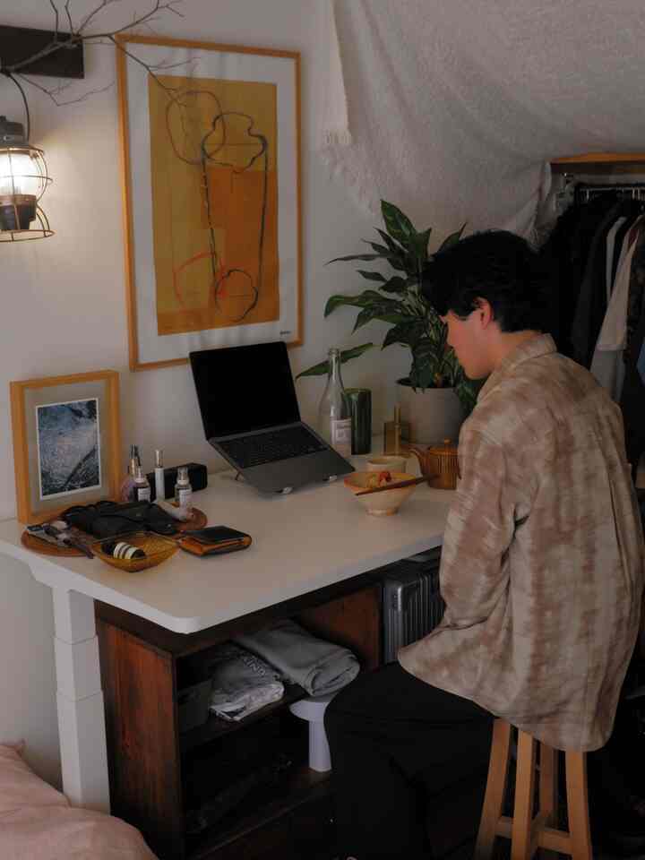 明るい白色の1人暮らしのワークスペース、白いデスクと茶色の木製スツールが配置された温かみのあるホームオフィスのインテリア