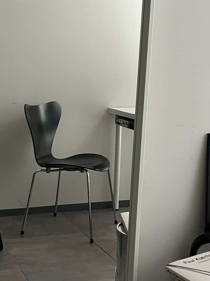 A modern dining chair in black and gray tones placed in a long and narrow room with a simple atmosphere