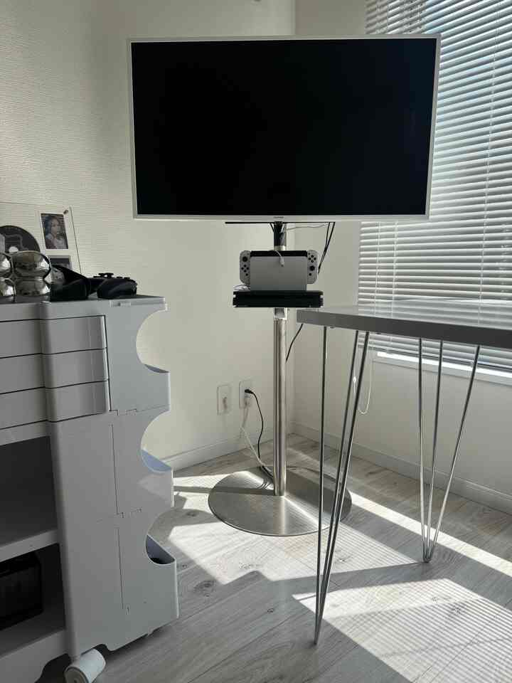 Bright toned white walls and white shelving, silver TV stand and table legs in a compact game room space