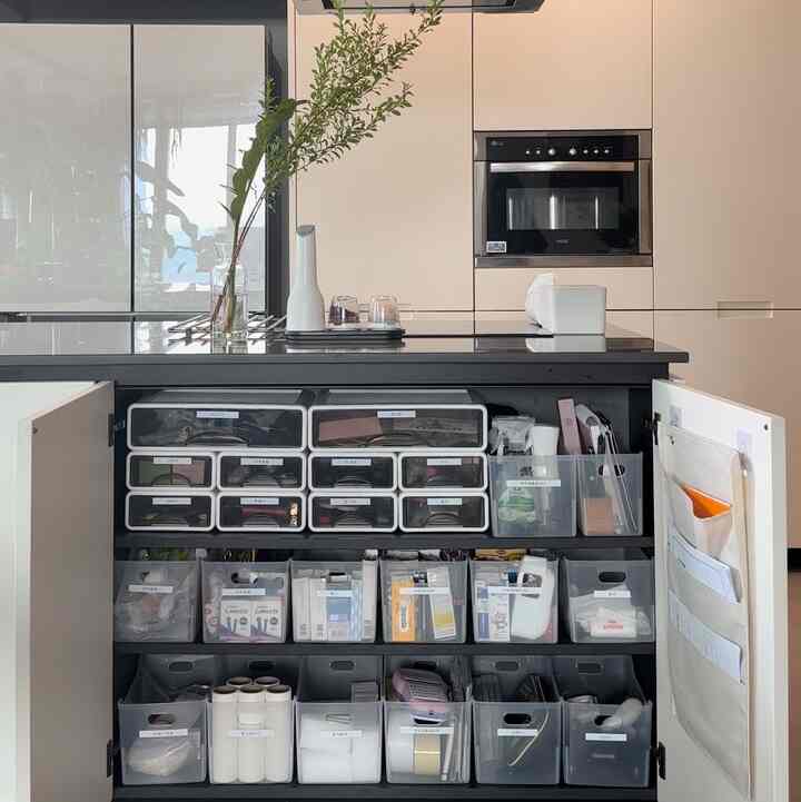 白と黒のトーンのキッチン収納キャビネット、整理ボックスとラベルで整頓された印象的な空間