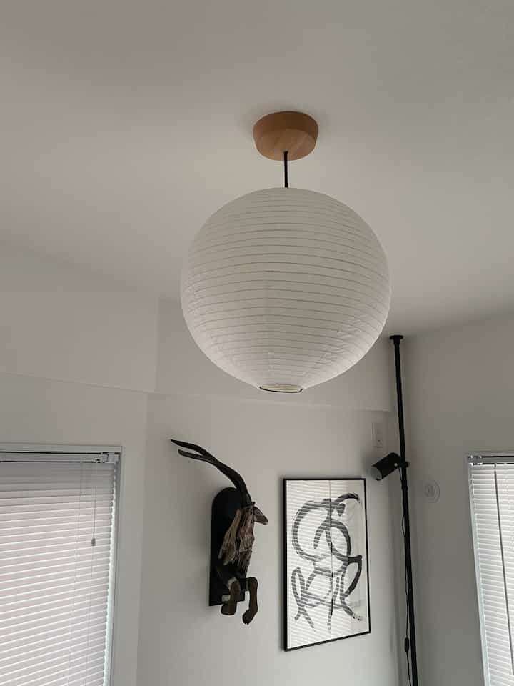 白とナチュラルトーンの書斎、中央の天井に紙製のペンダントライトが配置されたシンプルで落ち着いたインテリア