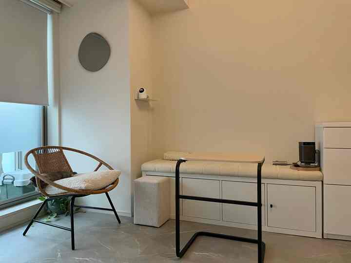 白とグレーのトーンの狭い部屋、ラタンチェアと円形の鏡が配置されたナチュラルモダンなインテリア