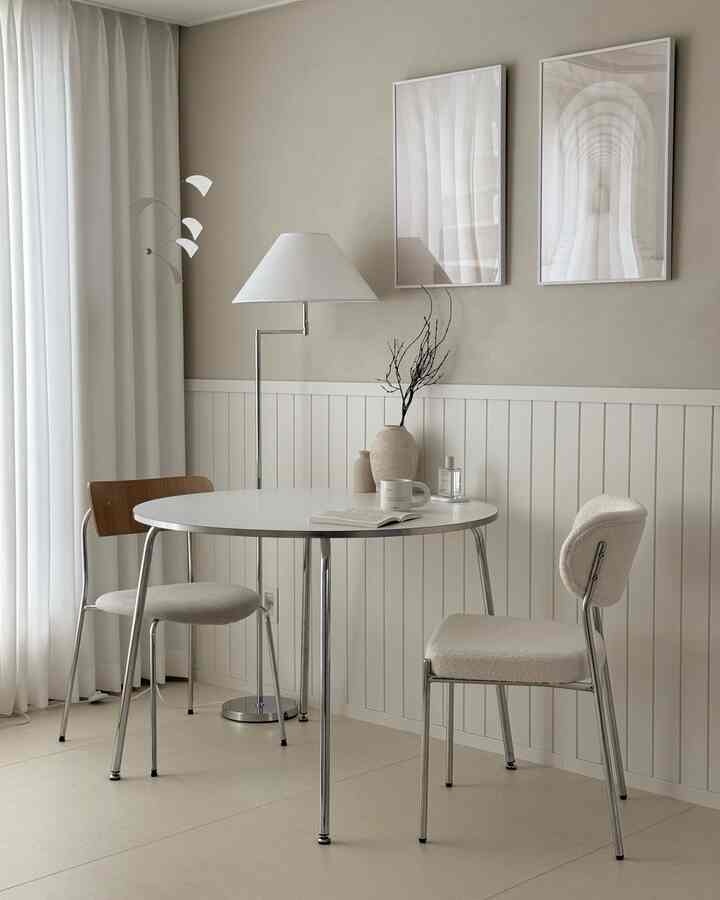 白とナチュラルカラーの調和が取れたダイニング、ブークレチェアと丸テーブルが置かれたシンプルでモダンな空間