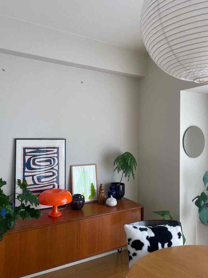 白と木目調のダイニングルーム、オレンジのテーブルランプと牛柄クッションを置いた椅子が配置された雰囲気のあるインテリア