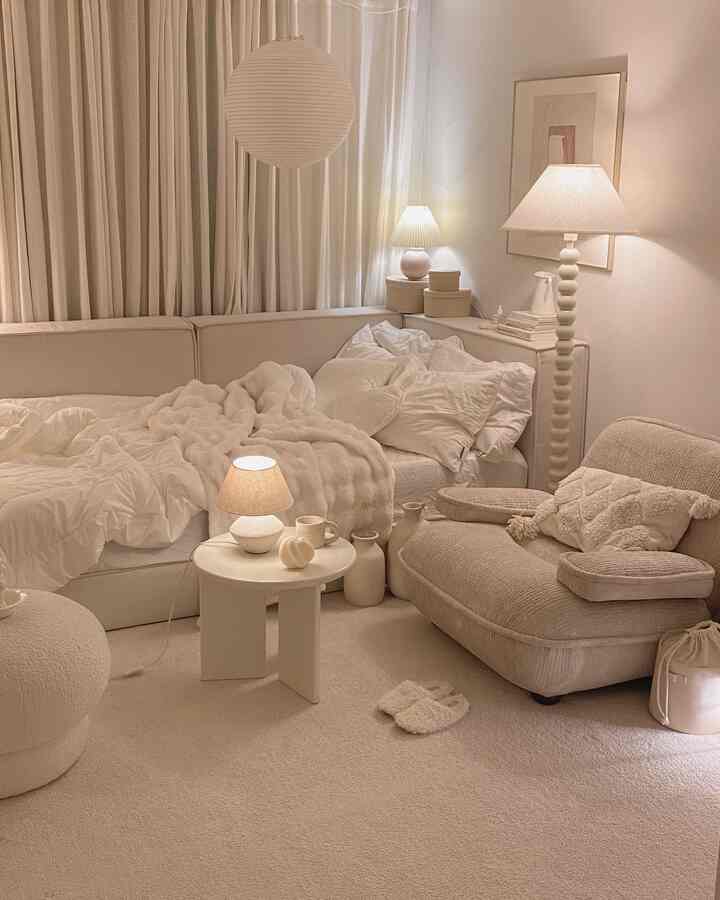 クリーム色調のリビングルーム、低めのソファとラグ、温かみのある照明と心地よいインテリア