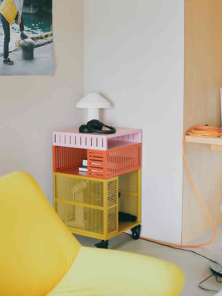 イエローとレッドが調和したコンパクトな部屋のコーナーに配置されたサイドテーブルとテーブルランプが印象的なモダンな空間