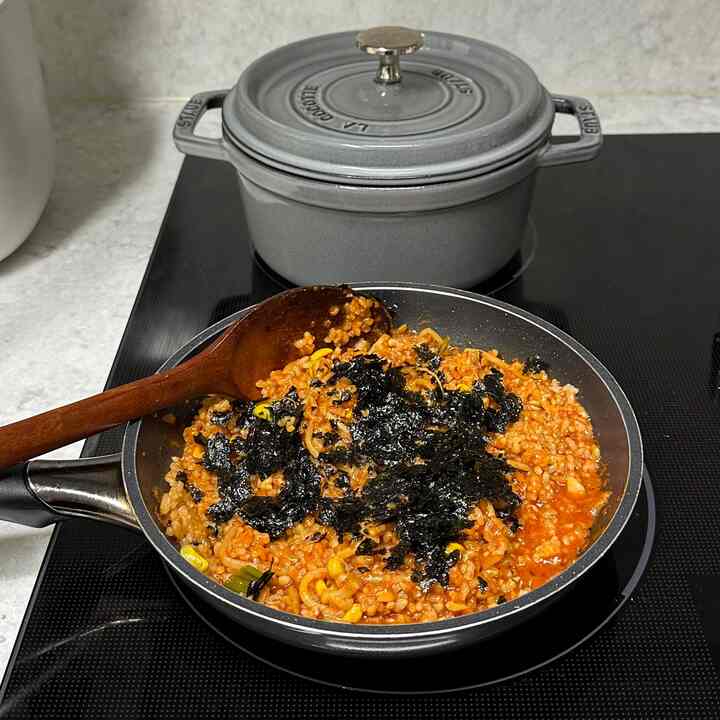 グレーのストウブ鍋が電気コンロの上にあり、黒いフライパンに海苔がのったチャーハンがあるキッチンの様子