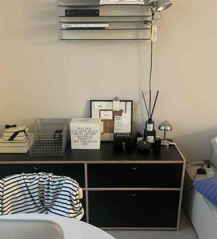 黒と白のトーンでまとめられたシンプルなドレッサーと棚、ディフューザーが置かれた清潔感のある室内