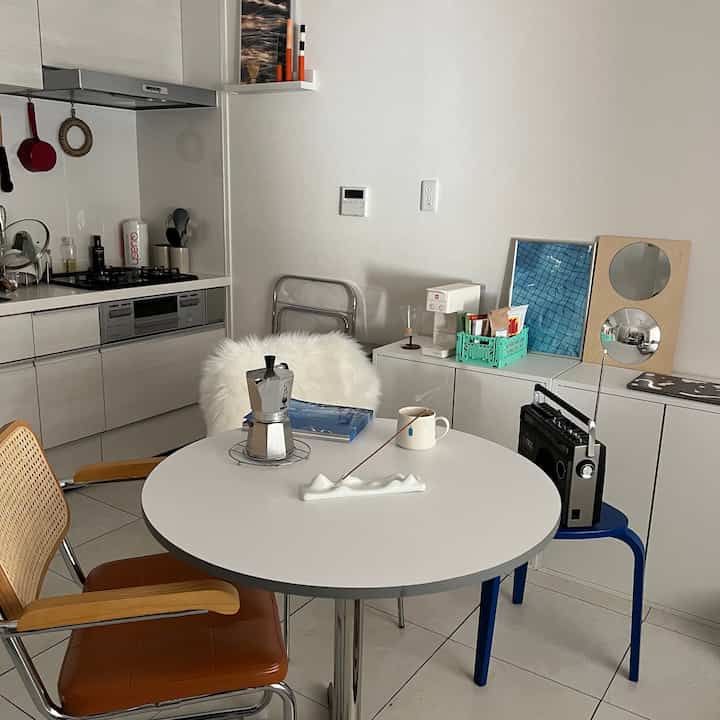 白と木目調が調和したワンルームのキッチン兼ダイニング、ミニマルでシンプルな雰囲気のあるインテリア