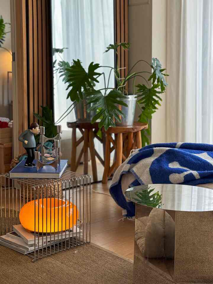 Natural style living room featuring green plant, silver table, and orange illuminated lamp